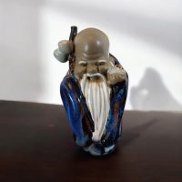Figura decorativa de sabio oriental en cerámica esmaltada 11 cm, de altura.